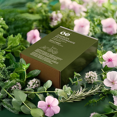 immagine del prodotto della sinergia detossinante ambientata su sfondo verde naturale con fiori rosa ed erbe aromatiche 